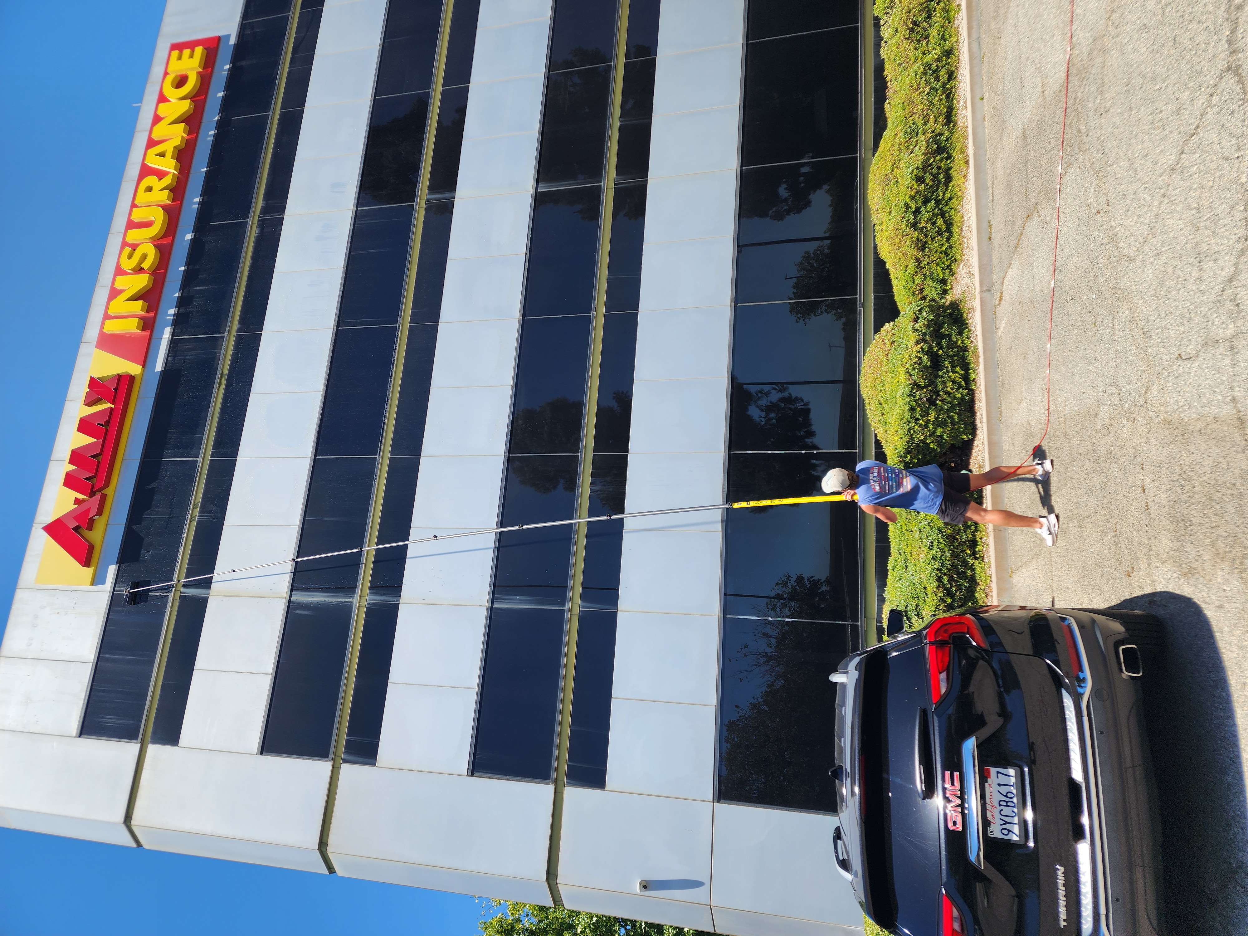 Technician cleaning the windows of the AMAX Insurance office building with a water-fed pole