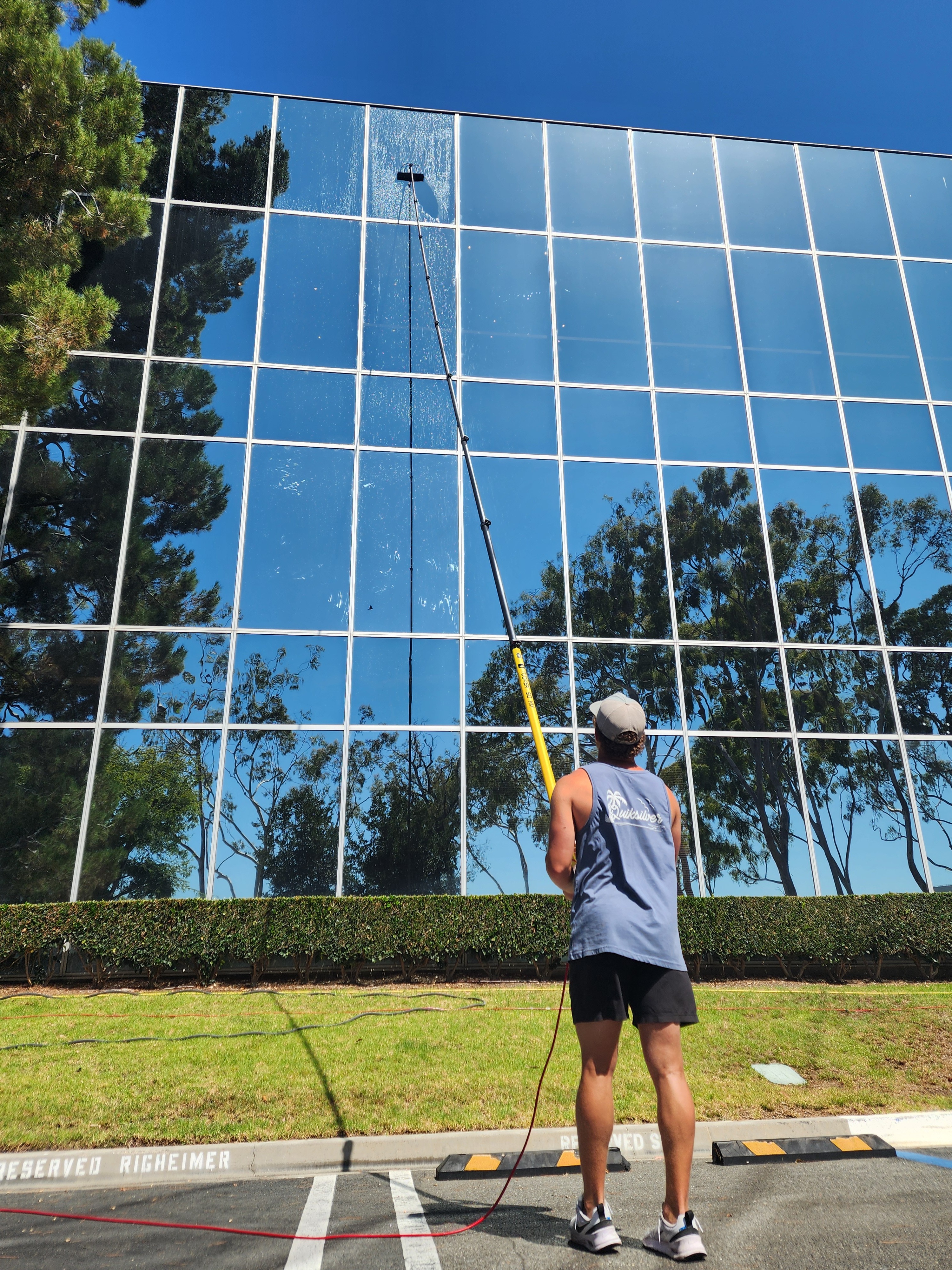 Technician cleaning a multi-story commercial building with a water-fed pole